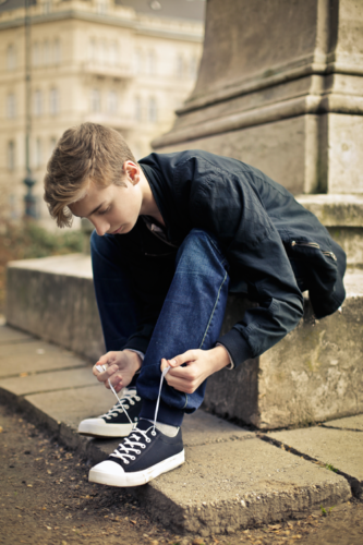 joven atando cordones de su calzado juvenil chikihuellas Joven atando cordones de su calzado juvenil Chikihuellas